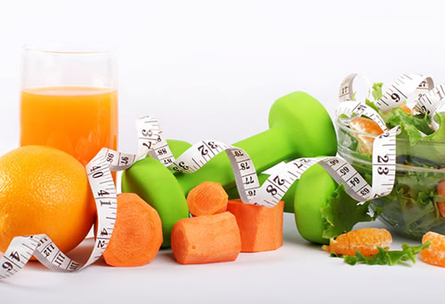 Weights, measuring tape, fruits and vegetables depicting weight loss