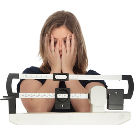 Woman covering eyes while on weight scale