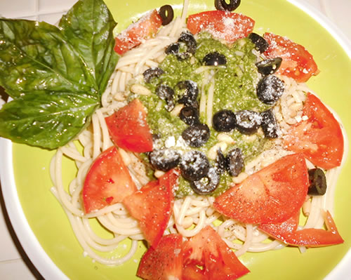 Add the pesto sauce to the hot pasta; garnish with the tomatoes, pine nuts, basil, olives, and cheese.