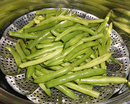 Place the washed green beans into a steamer in a large pan filled (below steamer level) with water.