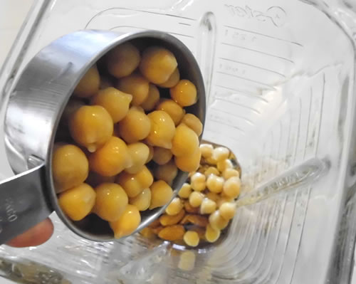 In a blender, combine the oil, almonds, and garbanzo beans.