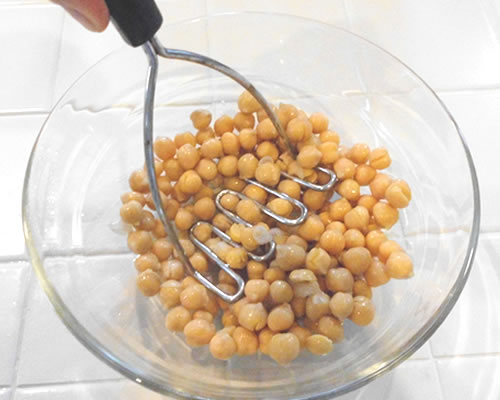 In a large bowl, mash the garbanzo beans with a fork or potato masher.