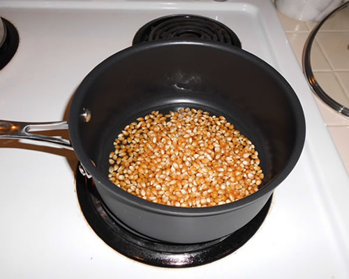 Heat the oil in a medium sized pan; add the popcorn and cook until popped.