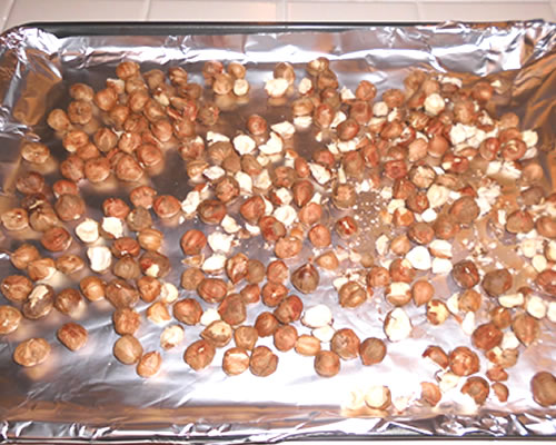 Spread the hazelnuts onto a baking sheet; bake at 350 degrees for 10 to 12 minutes until toasted; cool, and remove as much of the skins as possible.