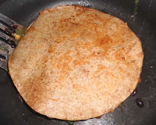 Cook the filled tortilla until lightly browned and heated through (and the cheese is melted); carefully flip over the tortillas and cook the other side. Remove from the heat, allow to set for 5 minutes, and slice the quesadilla into four wedges.