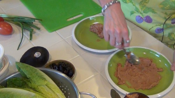 Spread the refried beans onto the bottom of the salad plates.
