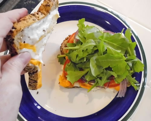 Remove the sandwiches from the pan; gently open each sandwich and top with the onion, tomatoes, and arugula.