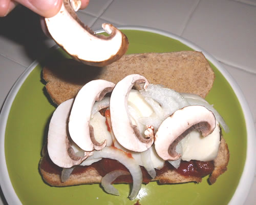 Top the sandwich with the mozzarella cheese, sliced onion, mushrooms, and more sauce; sprinkle with the Parmesan cheese.