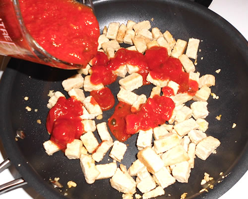 In a medium pan, heat the olive oil and cook the chicken tenders and garlic until very lightly browned; stir in the pasta sauce and remove from the heat.