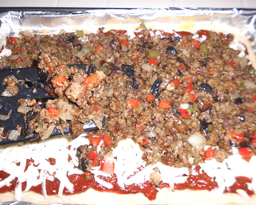 Spread the marinara sauce over the pizza crust; add the meat / veggie mixture, olives and cheeses; bake at 375 degrees for 10 minutes or until the crust is lightly browned.