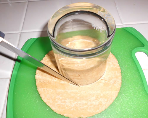 Using a biscuit cutter or glass rim, cut out circles in the tortillas (about 3 inches in diameter) and make three 1/4-inch slices in each one.

Note: Using corn tortillas, you should be able to cut two rounds from each tortilla.