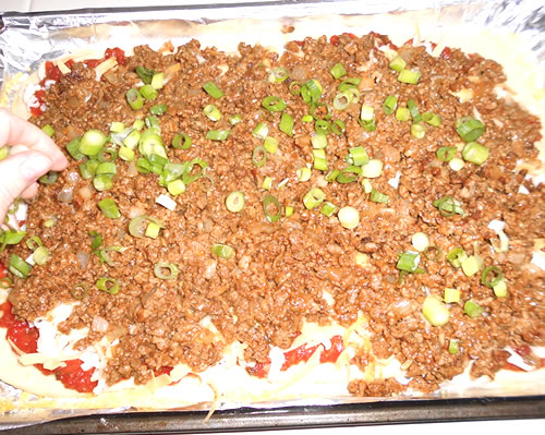 Top the pizza crust with the cheeses, crumble mixture, green onions and olives. Bake at 375 degrees for 10 to 20 minutes or until golden brown on the bottom.