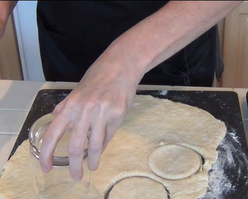 Roll the dough into 1/2 inch thickness; cut with a floured biscuit cutter (or use the rim of a drinking glass). Place the dough rounds onto an ungreased baking sheet and bake at 450 degrees for 10 to 12 minutes or until golden brown.