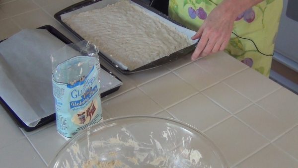 Using extra flour to prevent the dough from sticking to your hands, spread the dough onto the cookie sheets / pizza pans lined with parchment paper; top with the pizza ingredients or partially pre-bake the crust for 5 minutes at 375 degrees.