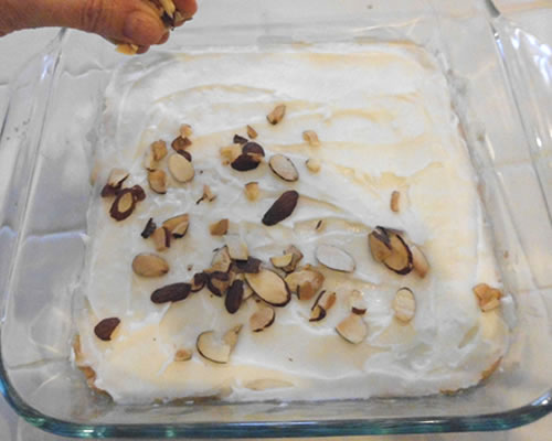 Once completely cooled, spread the almond cookie frosting evenly onto the baked and cooled filling; sprinkle the toasted almonds on top.