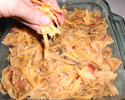 Turn the pasta mixture into an 8 x 8-inch greased baking dish; sprinkle with the remaining cheese and bake at 400 degrees for approximately 15 minutes or until lightly browned.
