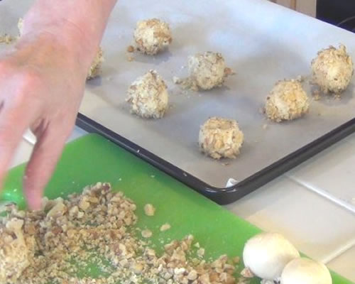 Form the dough into balls the size of a walnut; roll the balls into the walnuts. Place on lightly greased baking sheets; bake at 350 degrees for 5 minutes. Make a thumbprint in the center of the cookies; return to the oven to bake for an additional 8 to 10 minutes or until lightly browned on the bottom.